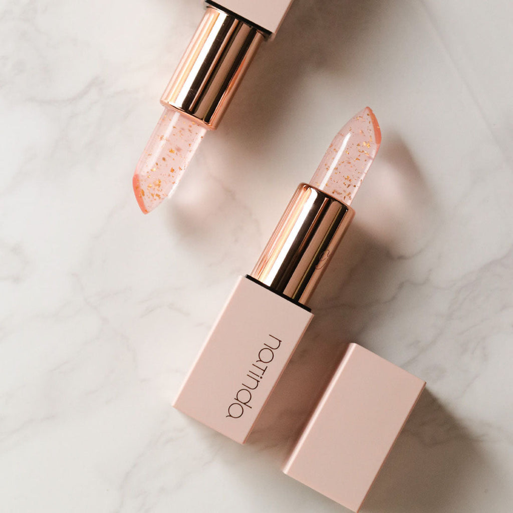 Lipstick with rose gold casing on a light marble background