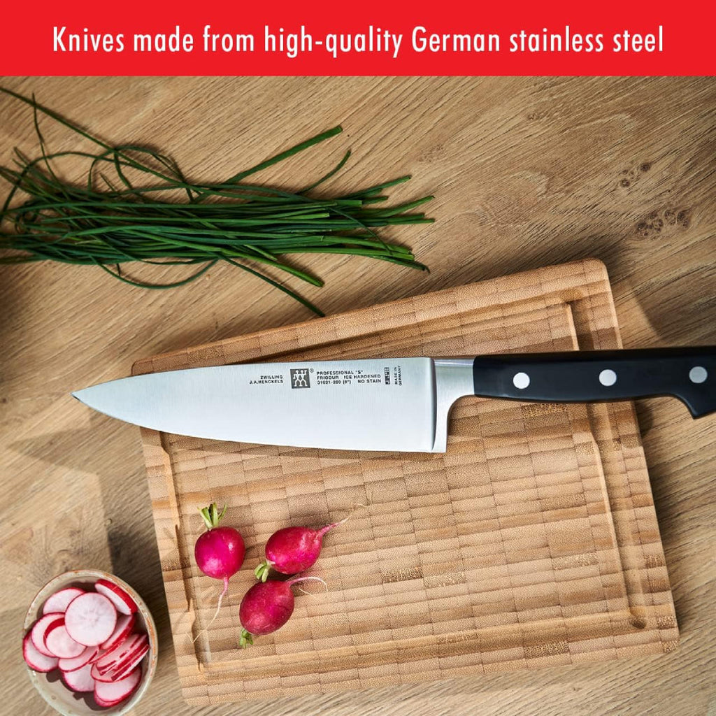 Zwilling Pro chef’s knife made with high-quality German stainless steel placed on a wooden cutting board with radishes and chives