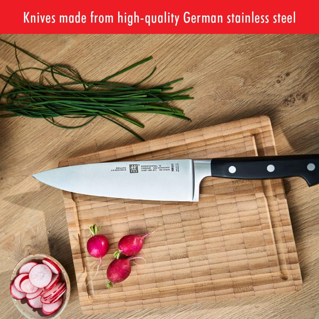 Zwilling Pro chef’s knife made with high-quality German stainless steel placed on a wooden cutting board with radishes and chives